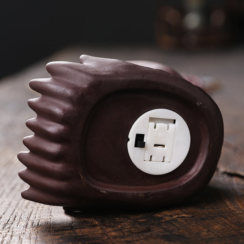 Braune elektrische Massagegerät-Füße mit Ein-/Aus-Schalter und Batteriefach auf Holzoberfläche