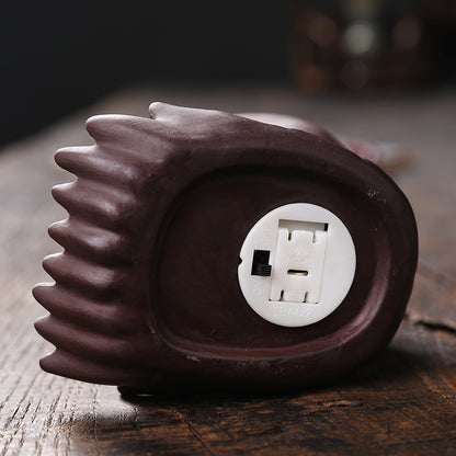 Braune elektrische Massagegerät-Füße mit Ein-/Aus-Schalter und Batteriefach auf Holzoberfläche