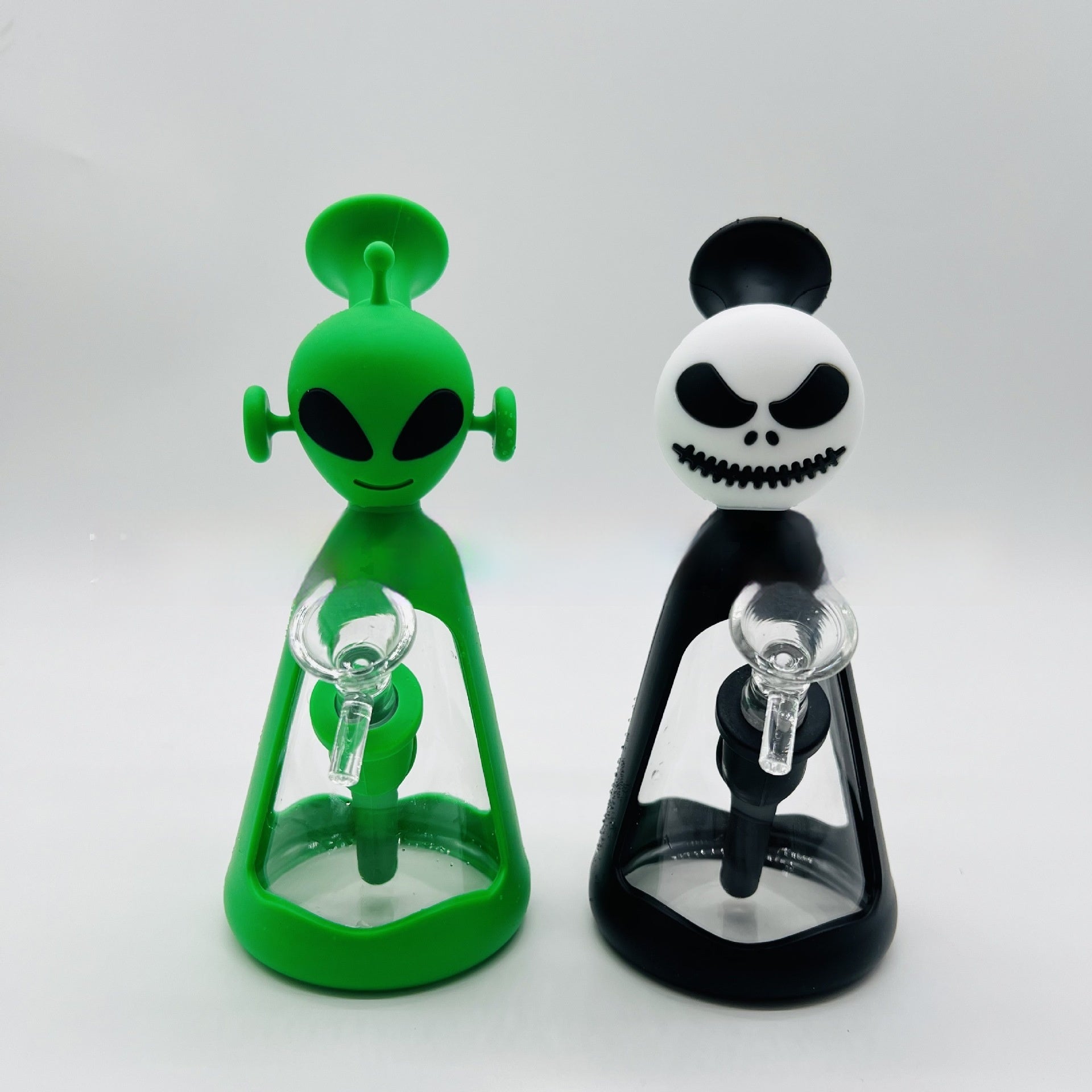 Grüne Alien- und schwarze Skelettbong mit transparentem Glas im modernen Design vor weißem Hintergrund