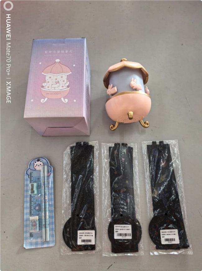 Nachtlicht mit Hasenmotiv, Verpackung, drei Ersatzlampen und zwei blaue Stifte mit Eulenmotiv auf grauem Untergrund